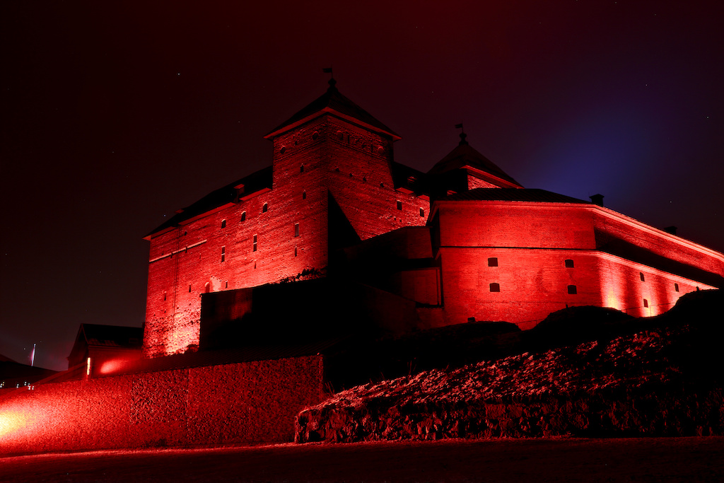 A medieval Häme Castle in bright red and artistic lightning